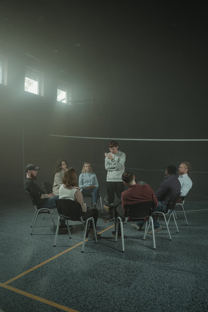 A group of adults engaged in a therapy session within a calm, smoky indoor environment.