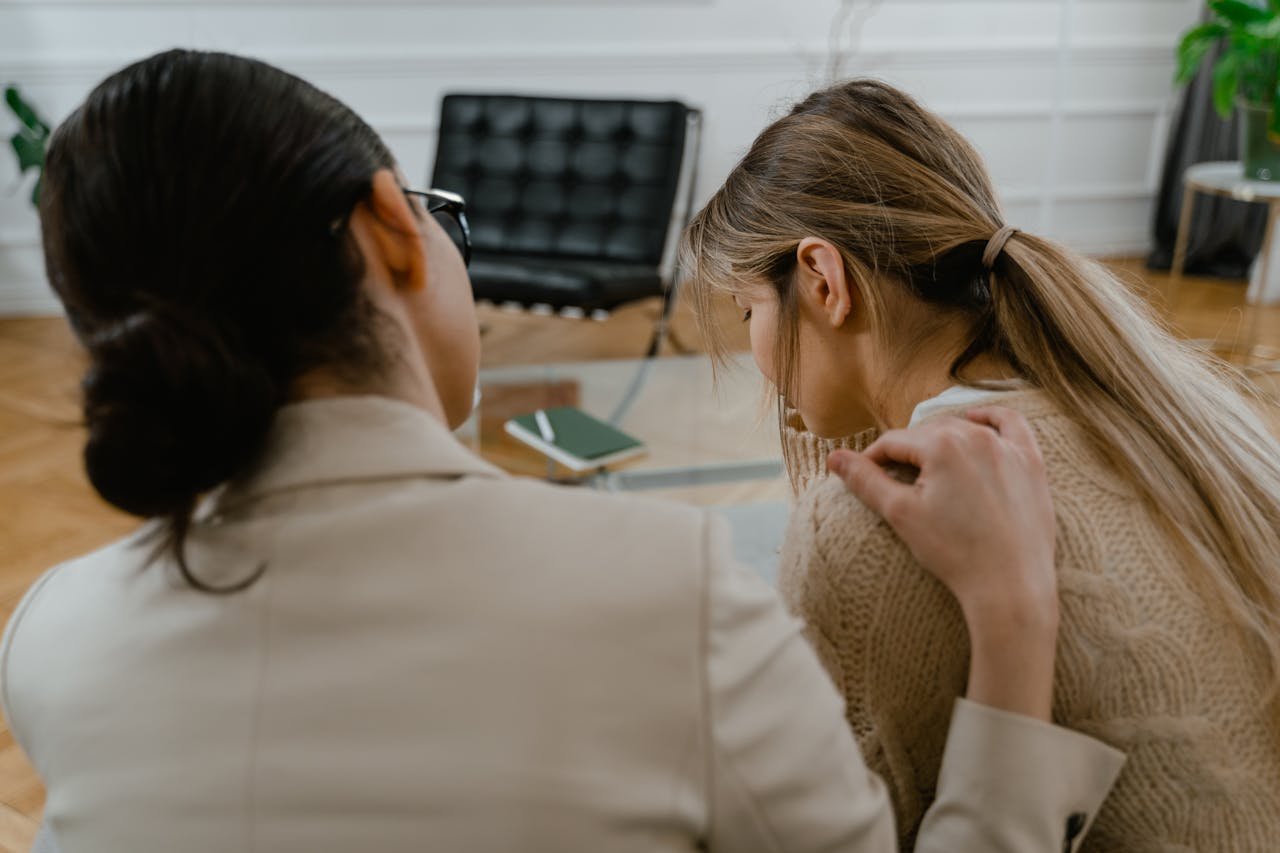 Two women sitting together, offering emotional support in a comforting setting.